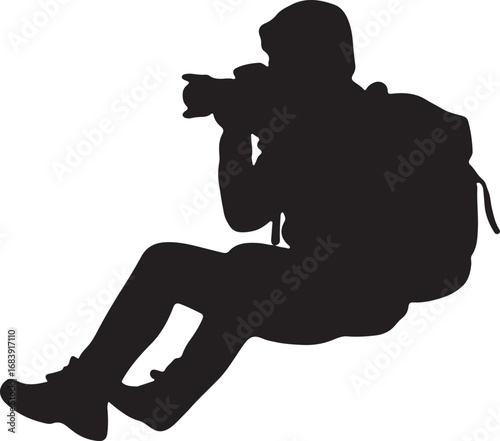 Silhouette of a photographer with a backpack taking a picture camera sitting