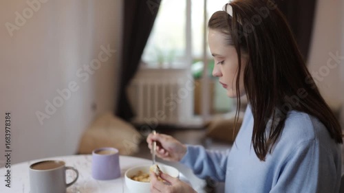 a young woman having breakfast at home at the table
