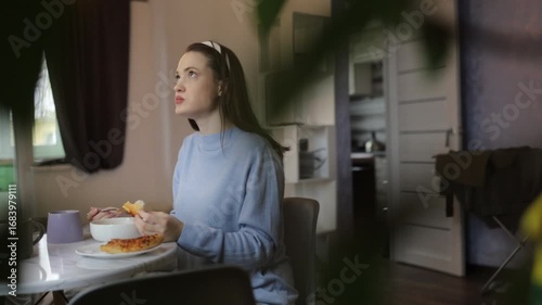 a young woman having breakfast at home at the table