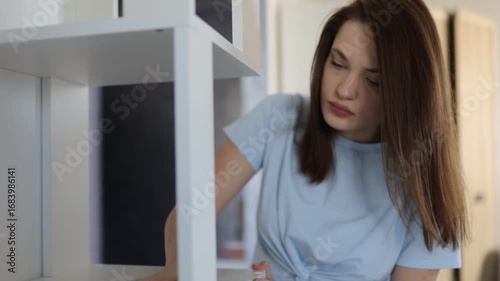 A woman cleans and dusts her house with a rag
