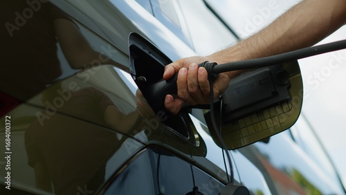 Fotografie Close up of driver recharging EV vehicle battery powering sustainable electric motor, low angle shot