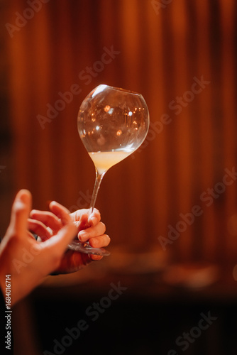 Εκτύπωση καμβά Elegant hand holding wine glass at cozy candlelit dinner with floral decor