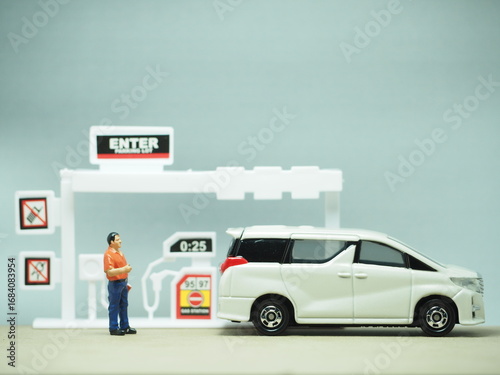 Mini toy of action figure at table with blurred background. Miniature photography concept design. Vehicle at gas station.