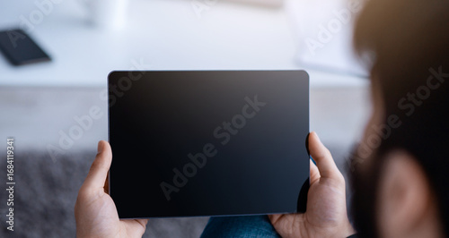 Fotografija Unrecognizable guy using digital tablet with empty screen, browsing internet or showing new app, sitting on floor at home