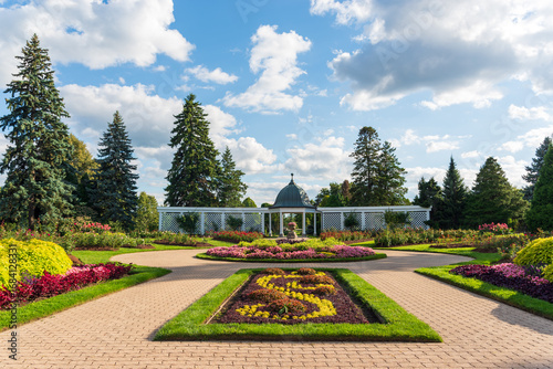 Beautiful landscaped gardens with colorful flowerbeds, pathways, and a pavilion at the Niagara Parks Botanical Gardens.