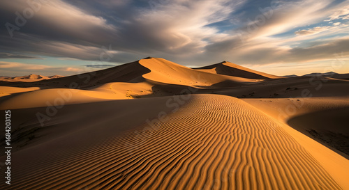 Fototapeta Naklejka Na Ścianę i Meble -  Golden Sand Dunes at Sunset with Rippled Patterns and Dramatic Sky.
