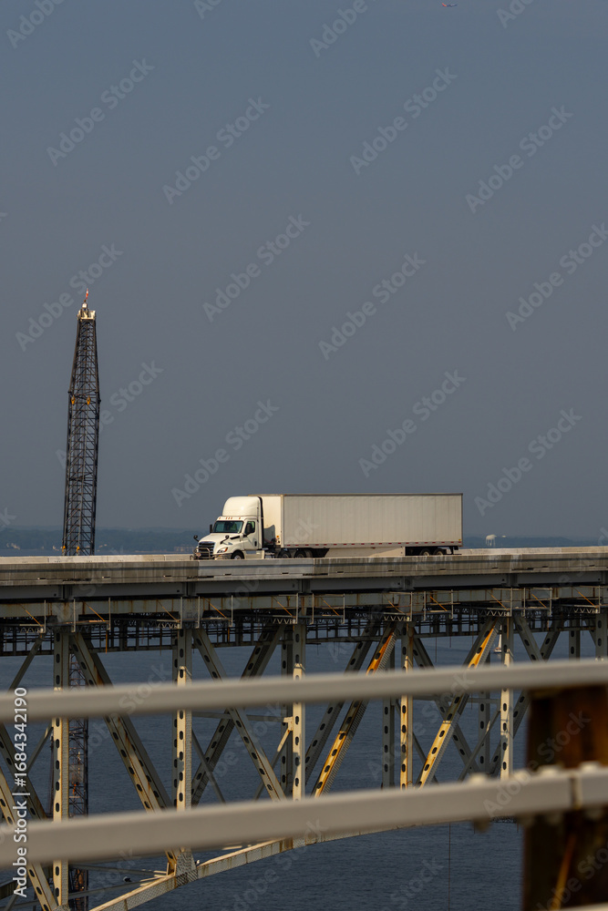 Obraz premium Truck driving across the bridge. Lorry transporting. Cargo trailer. Logistics truck, international shipment. Truck transport. Semi truck containers, logistics industry. Trucks lorry logistic concept.