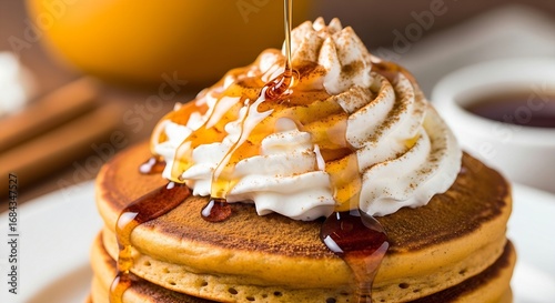 a stack of fluffy pumpkin spice pancakes, generously topped with whipped cream and a sprinkle of cinnamon and nutmeg. A rich maple syrup drizzle is frozen in motion.