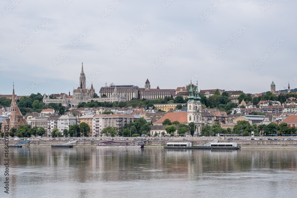 Obraz premium Budapest, Hungary – View of the Danube River with the Buda side in the background. Far in the distance, Fisherman’s Bastion crowns Castle Hill with its fairytale-like silhouette.