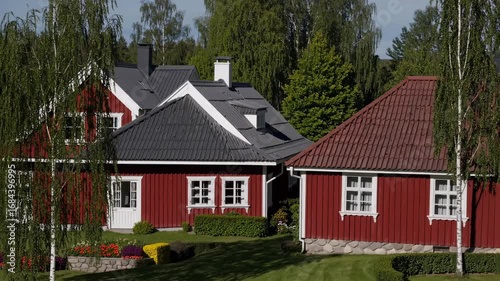 Wallpaper Mural Aerial video view of a serene countryside landscape with red houses, lush greenery, and a reflective pond under a sky dotted with fluffy clouds. Torontodigital.ca