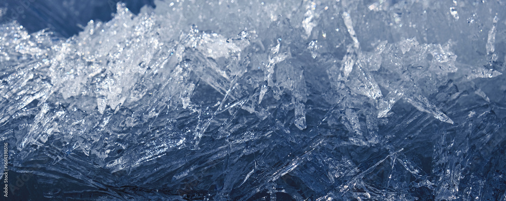 Obraz premium Arctic ice. Monochrome frozen background with light and shadow. A scattering of large long ice crystals in the form of needles on the river in winter.