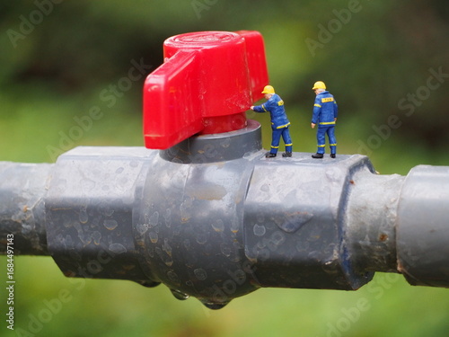 Mini toy of action figure at table with blurred background. Miniature photography concept design. Minifigure Plumbing crew character with wrench tool conceptual. Worker with pipe line.