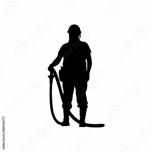 Silhouette of a construction worker pouring concrete with a hose