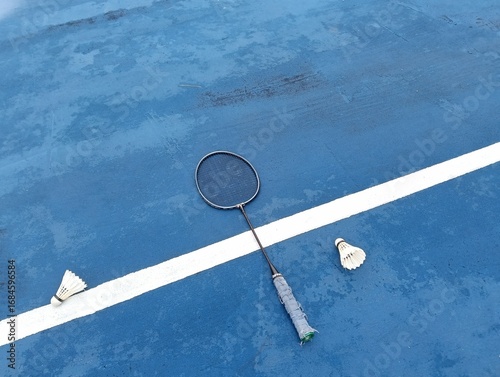 shuttlecock and badminton racket on a blue  badminton court outside the line on blue background close up. Photo taken in Malaysia