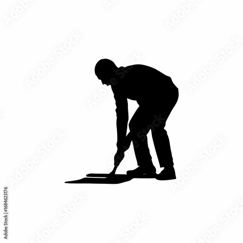 Silhouette of a construction worker spreading concrete on a floor