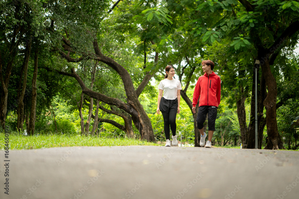Obraz premium Young couple jogging together in the park, promoting healthy lifestyle and family bonding