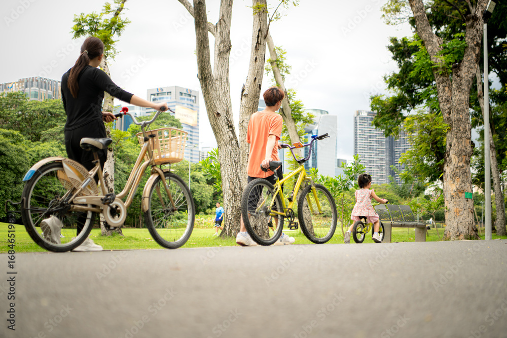 Obraz premium Parents and little girl to ride balance bike in park on the holidays of the week