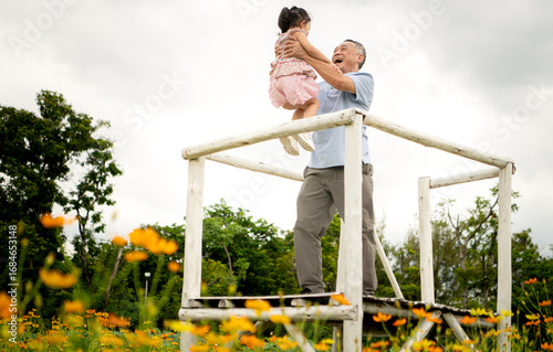 Grandfather and granddaughter stand on scaffolding and admire the beautiful flowers