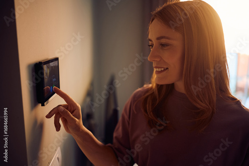 Obraz na płótnie Happy woman using video intercom in modern home.