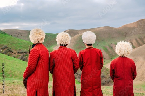 Fotografie Traditional Turkmen Men in Red Robes and Fur Hats in Nature