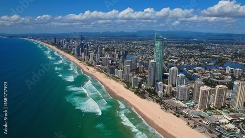 A breathtaking aerial view of Gold Coast, Australia, showcasing the stunning coastline, high-rise skyline, and beautiful sandy beaches. The turquoise ocean waves crash along the shore