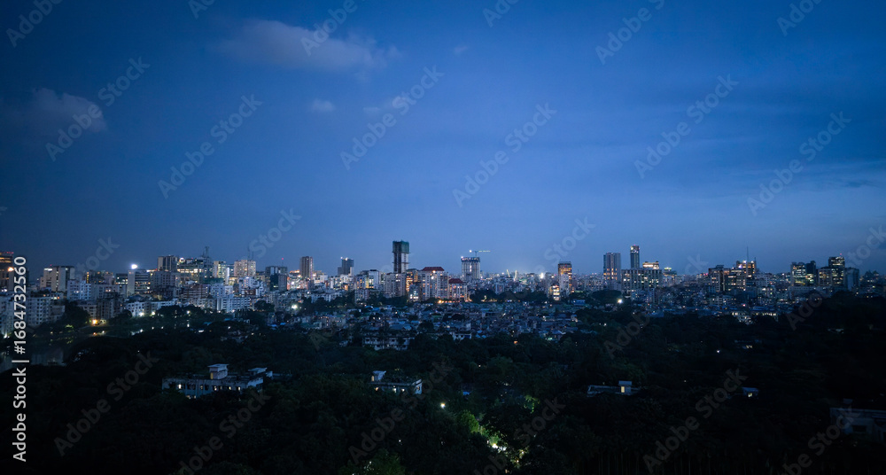 Naklejka premium Night view at Dhaka city. Dhaka city skyline at night with glowing urban lights, beautiful modern cityscape of downtown capital, panoramic twilight view of illuminated buildings and blue evening sky