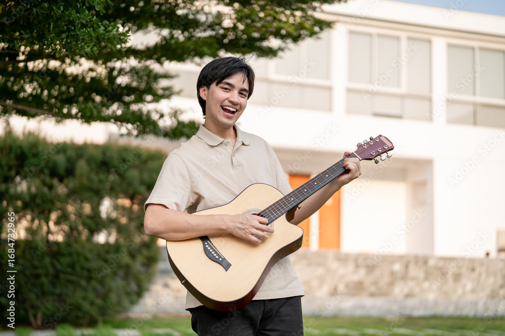 Fototapeta premium Portrait of Asian man musician playing an acoustic guitar in the garden. 