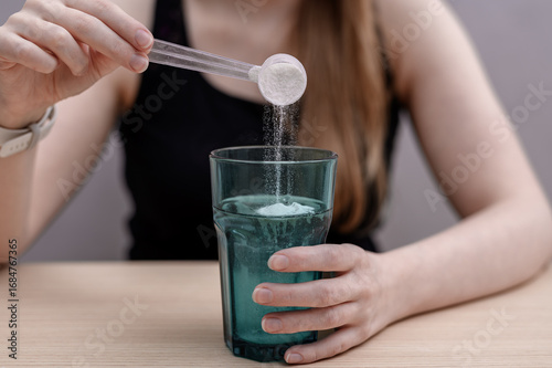 A woman dissolves creatine powder in a glass of water after training.