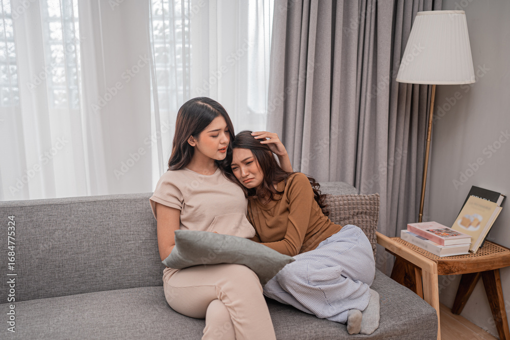 Obraz premium Two women share a warm, intimate moment on a cozy sofa, highlighting friendship.