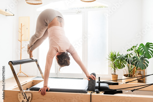 Φωτογραφία Woman practicing pilates performing jackknife exercise on reformer bed