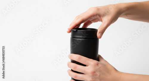 Hands opening a minimalist black insulated travel mug, symbolizing sustainable hydration and the daily ritual of preparing beverages for an active lifestyle