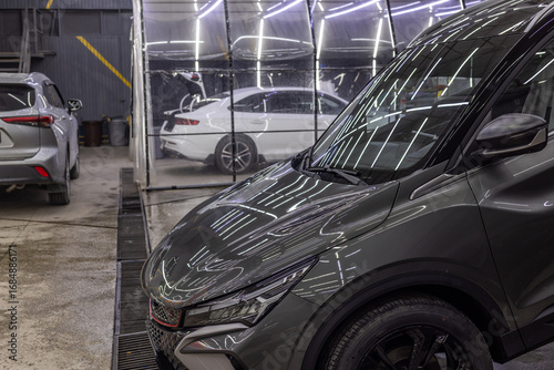 Dark gray SUV parked in indoor car wash detailing studio during daytime
