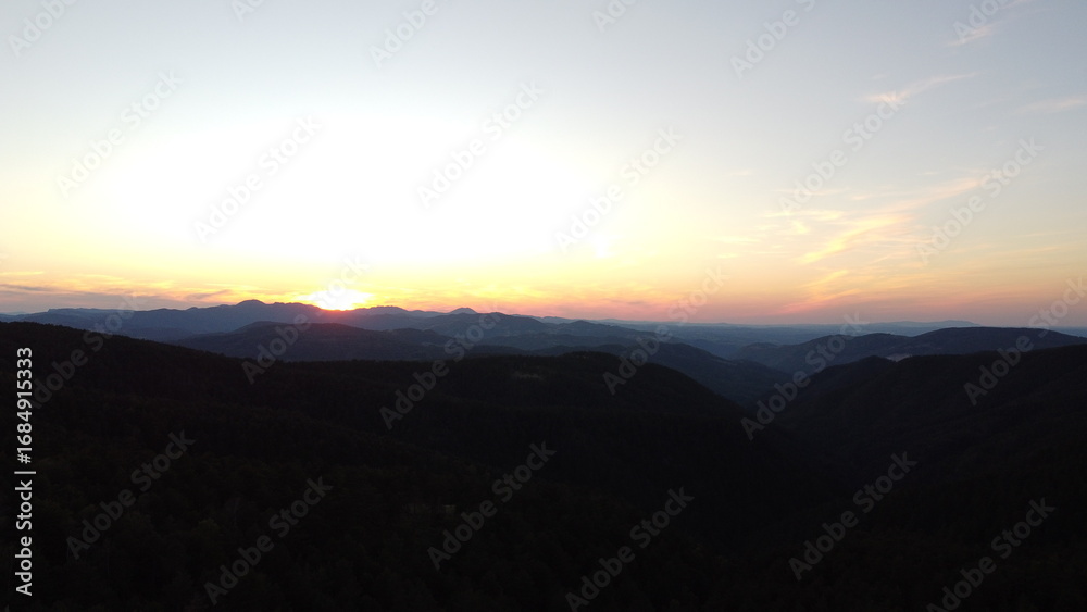 Fototapeta premium Sunset Over Mountain Range and Forest – Aerial View Landscape 
