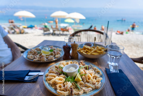 Fototapeta Naklejka Na Ścianę i Meble -  eating fried squid calamari with a sea view from the beach bar in croatia