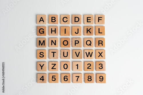 Alphabet letters and numbers on scrabble wooden pieces, isolated on white.