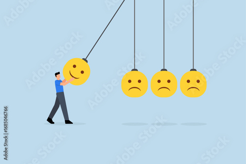 Optimistic, man holding a smiling face pendulum ball to strike other frowning faces