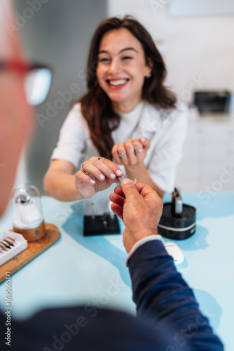 Audiologist is presenting a hearing aid device to a senior patient during a consultation in a modern audiology clinic, discussing options for improving hearing health
