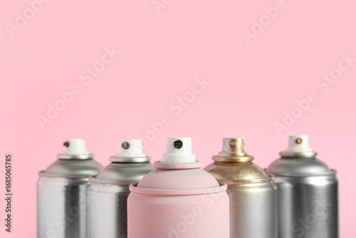 Spray paint cans on pink ba...