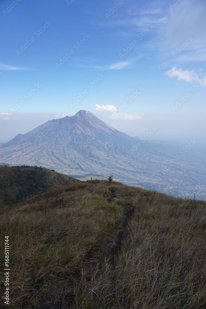Fototapeta premium The savannah on Mount Merbabu with Mount Merapi in the background. Central Java, Indonesia