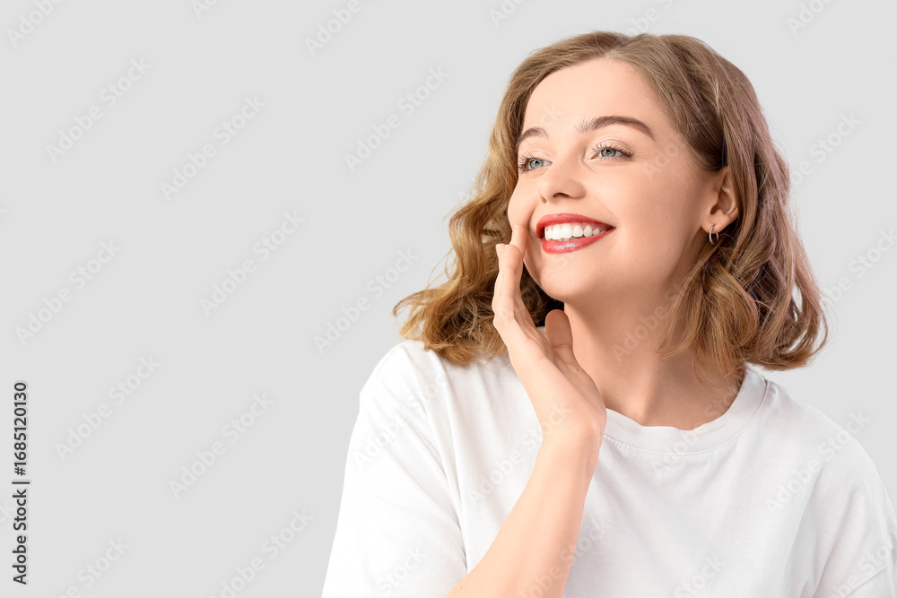 Fototapeta premium Smiling young woman with bob hairstyle on grey background