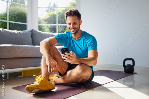 Sporty man checking his phone during home workout