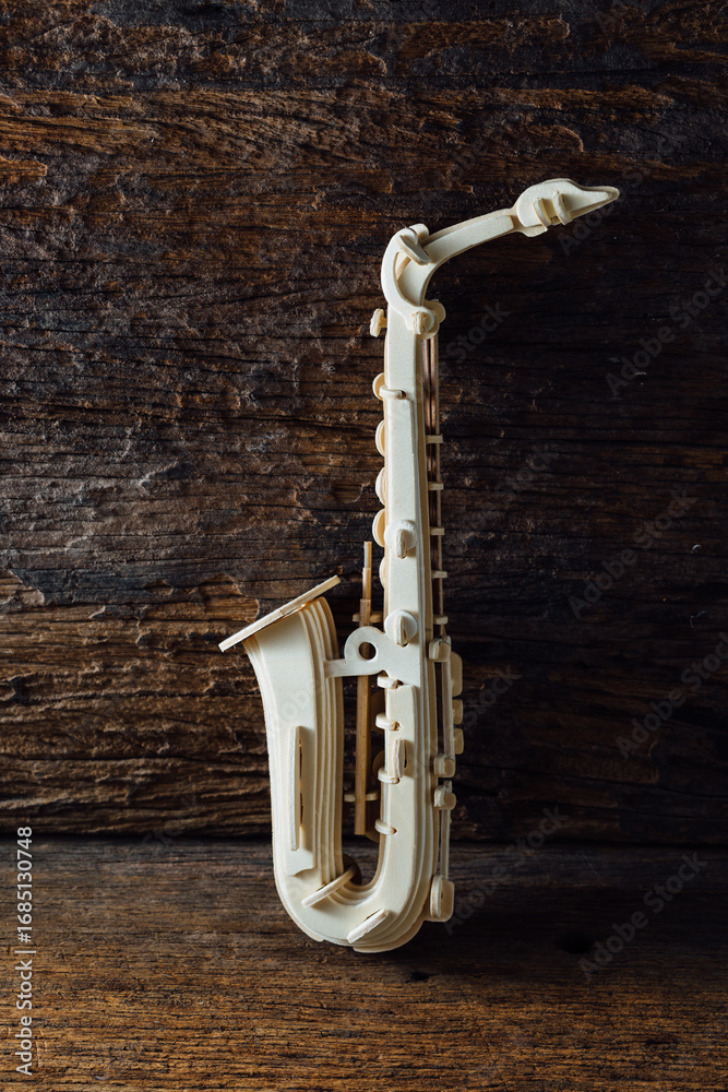 Naklejka premium Elegant Wooden Saxophone Sculpture on Rustic Wooden Background