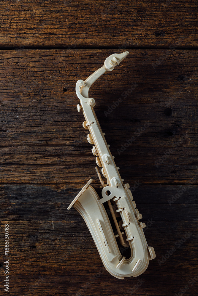 Naklejka premium Elegant White Saxophone on Rustic Wooden Background with Texture