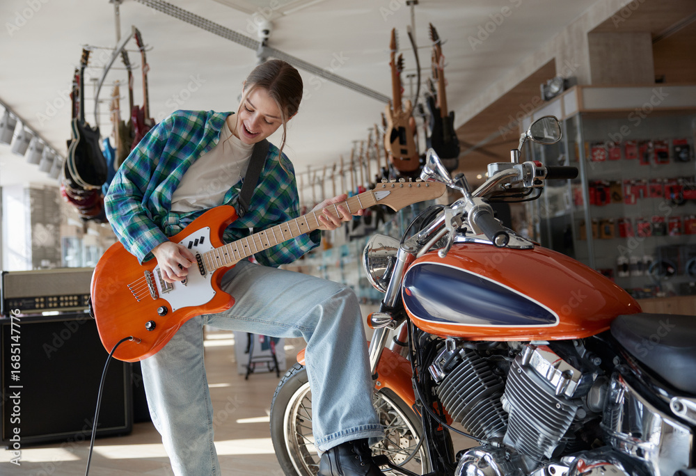 Fototapeta premium A woman plays guitar while sitting on a motorcycle