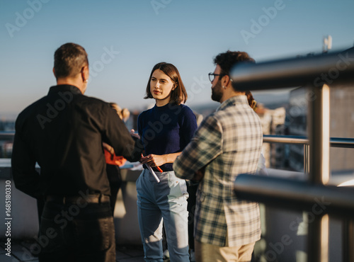 Fotografía Business colleagues engage in a brainstorming session on a rooftop balcony at sunset, embracing diversity and creativity in a relaxed atmosphere