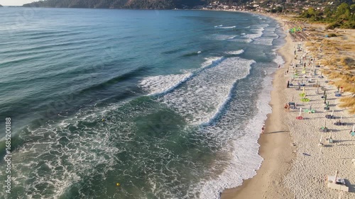 Woman walking on Golden beach near sea at Thassos Island, Greece. Amazing beach with clear blue water. Aerial panoramic drone view from above, top view from drone. Summer holidays Europe
