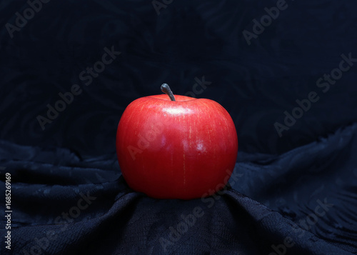 Red apple on black fabric background