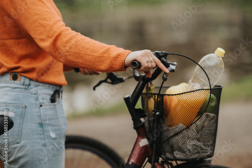 Bilde på lerret A side view capture showing someone gripping a bicycle handle, with a basket containing shopping items such as a bottle, indicating an active and eco-friendly lifestyle