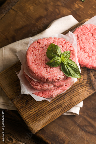 Raw burger patties on wooden background