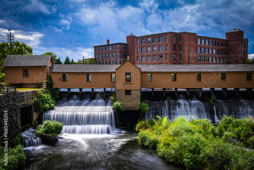 Autumn landscape after a rainstorm in Lowell, Massachusetts. Blue clouds drift above the Lower Locks Gatehouse and Merrimack River, a Historic Civil Engineering Landmark within the National Park.